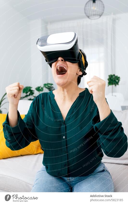 Frau genießt eine Virtual-Reality-Erfahrung zu Hause Virtuelle Realität VR Headset Technik & Technologie Aufregung Freude heimwärts Wohnzimmer Sofa Begeisterung