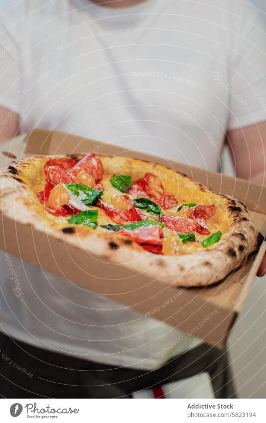 Frisch gebackene Pizza in einer von einer Person gehaltenen Lieferbox Versand Kasten Karton Lebensmittel frisch Beteiligung anonym gesichtslos Ernte Imbissbude