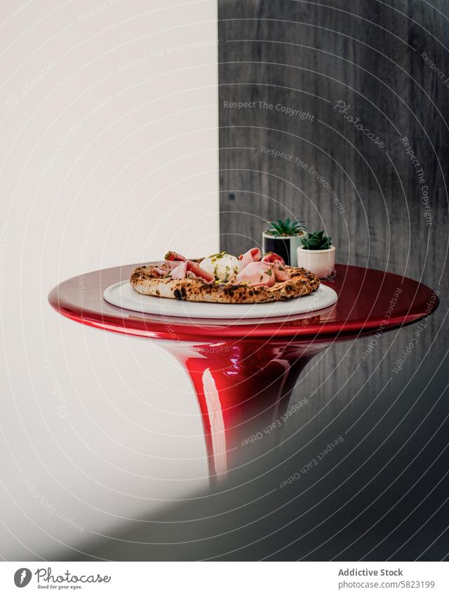 Handwerklich hergestellte Pizza auf einem roten Tisch in einer modernen Pizzeria Kunstgewerbler Lebensmittel Restaurant speisend Italienisch Küche Belag Tomate