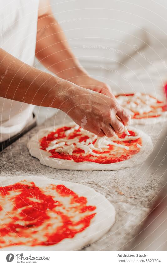 Zubereiten von Pizza in einer professionellen Küche Küchenchef anonym Pizzeria Vorbereitung Saucen Käse Teigwaren Essen zubereiten Hand Belag Lebensmittel