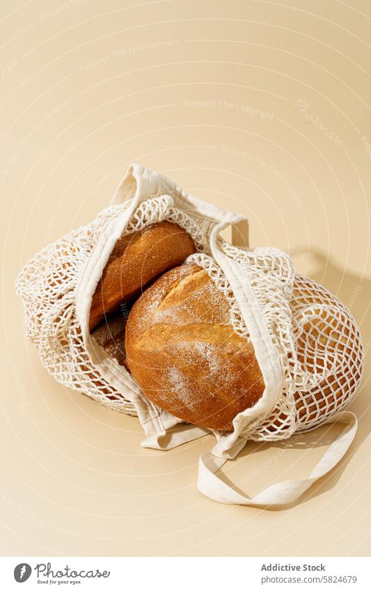 Frische Sauerteigbrote in einer wiederverwendbaren Tasche auf beige Brot umweltfreundlich Hintergrund backen Handwerklich Brotlaib knusprig frisch gewebt