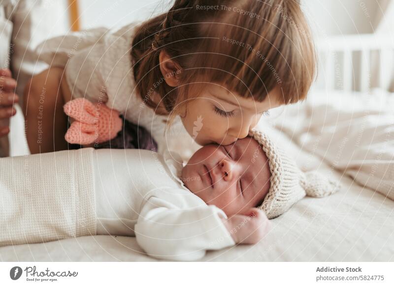 Kleine Schwester gibt ihrem schlafenden neugeborenen Bruder einen sanften Kuss Kleinkind Baby Zuneigung Liebe Zärtlichkeit Momente Familie Geschwister Pflege