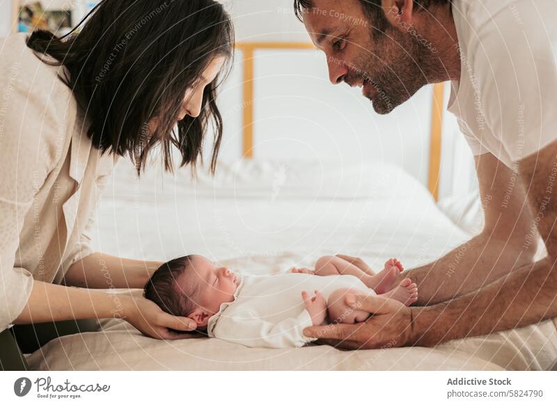 Neue Eltern, die ihr neugeborenes Baby im Bett anhimmeln Mutter Vater Liebe Säugling Pflege Familie Zärtlichkeit Zuneigung Bonden Wiege Starrer Blick schlafen