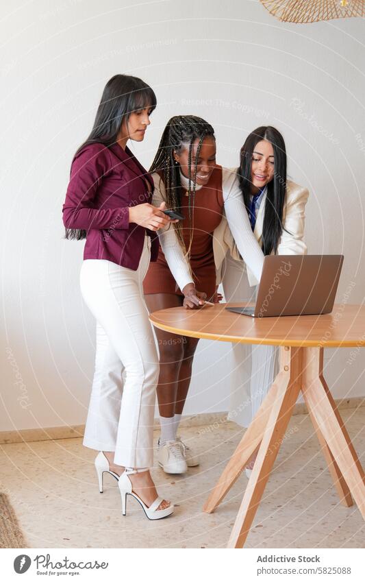 Drei Frauen, die zu Hause mit einem Laptop an einem Projekt arbeiten Arbeit heimwärts Business zusammenarbeiten multiethnisch vielfältig Schreibtisch