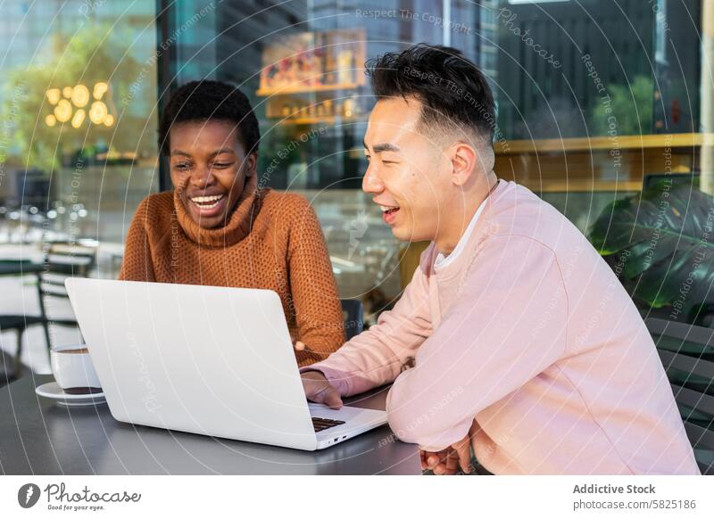 Unterschiedliche Studenten lachen gemeinsam über einen Laptop in einem Café Schüler Freund Lachen Technik & Technologie Apparatur Frau Gerät Mann Bildschirm
