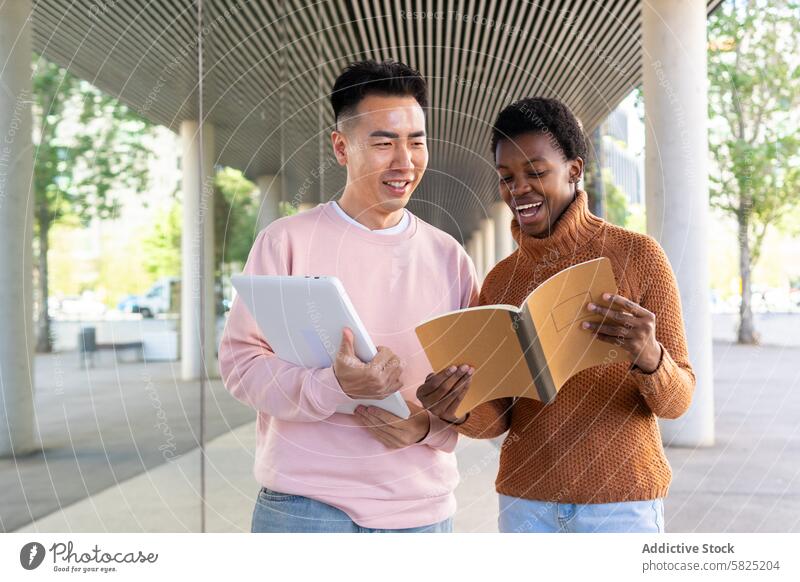 Multikulturelle Studenten tauschen im Freien Ideen aus Schüler multikulturell Bildung Besprechung asiatisch Afrikanisch Tablette Notebook Campus Teilen heiter