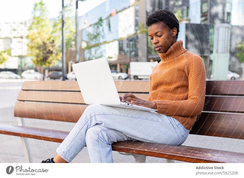 Afroamerikanischer Student arbeitet im Freien an einem Laptop Schüler Frau Afroamerikaner Bank fokussiert Arbeit Technik & Technologie Sitzen vertieft Aufgabe