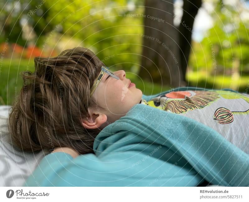 Junge liegt auf einer Wiese mit geschlossenen Augen glückliches kind Kind natürlich 3-8 Jahre Kindheit Außenaufnahme Kopf Porträt Mensch Haare & Frisuren liegen