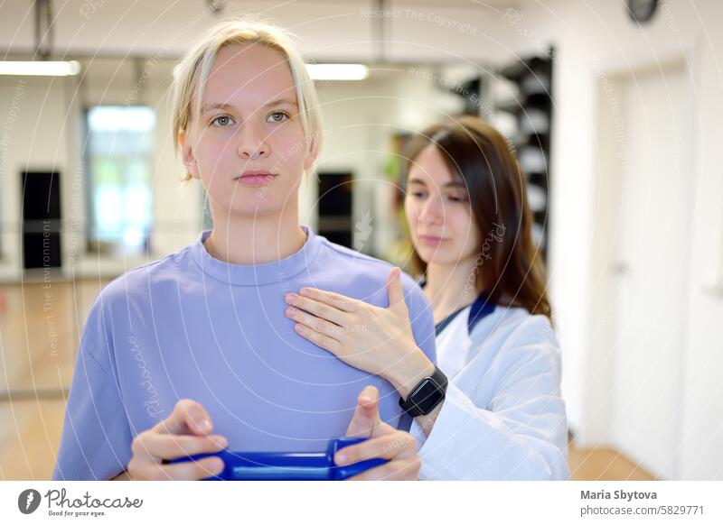 Der Reha-Arzt führt den Termin des Patienten in der Turnhalle durch. Der PMR-Spezialist schult den Patienten in der korrekten Ausführung der Wiederherstellungsübungen.