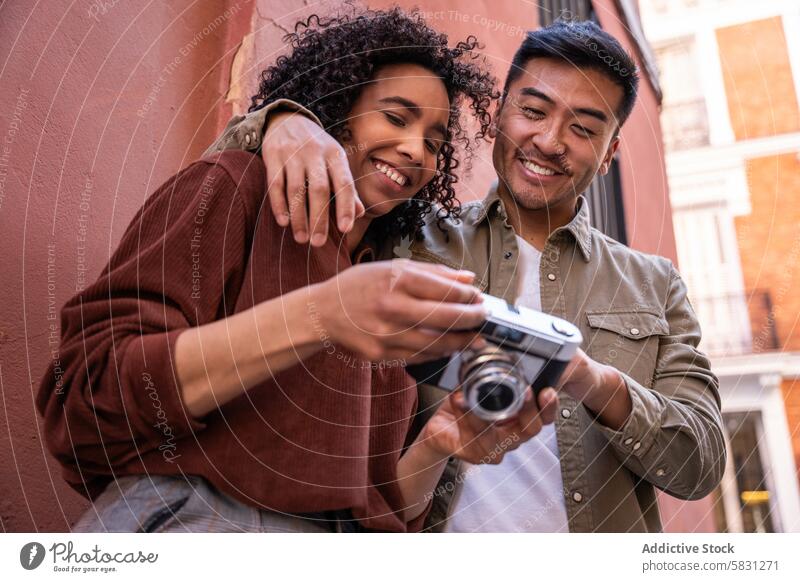 Ein multiethnisches Paar erkundet Madrid und betrachtet die Fotos der Kamera Chinesisch hispanisch Spanien Fotokamera Fotografie reisen Großstadt urban
