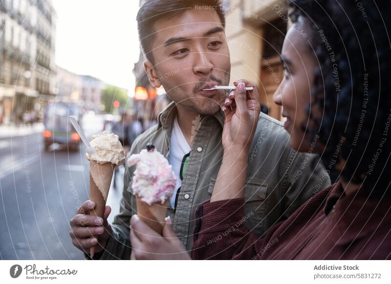 Ein multiethnisches Paar genießt ein Eis in einer Straße in Madrid Mann Frau Chinesisch hispanisch Speiseeis Spanien sonnig Tag Großstadt urban Romantik Liebe