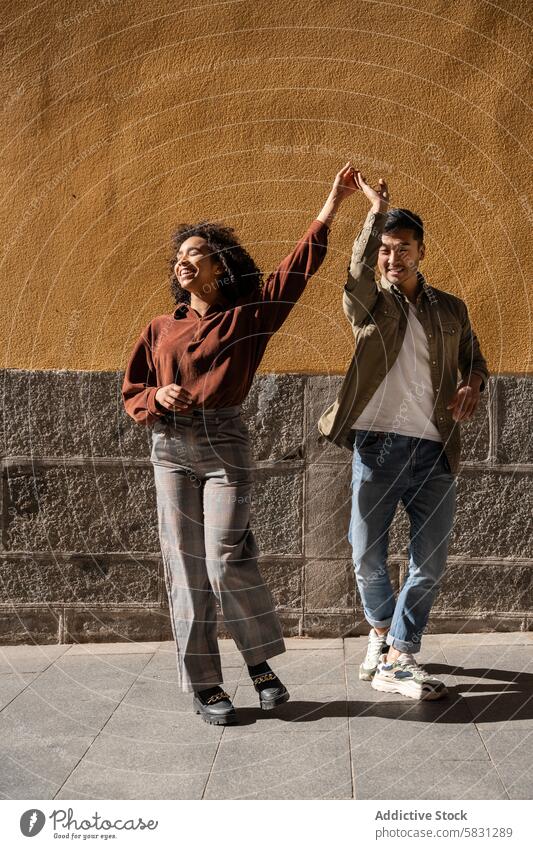 Fröhliches multiethnisches Paar tanzt auf den Straßen von Madrid Tanzen Freude Fröhlichkeit urban Großstadt Spanien multikulturell Chinesisch hispanisch Liebe
