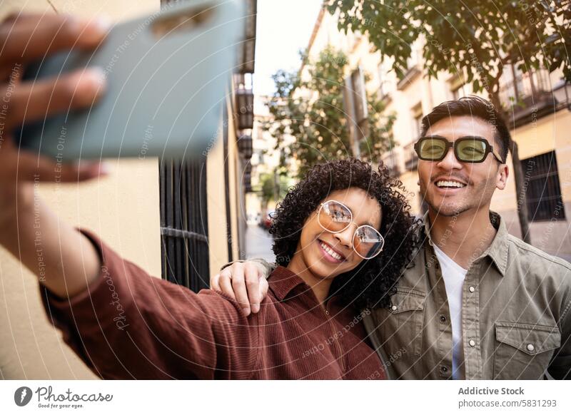 Ein multiethnisches Paar macht ein Selfie in einer belebten Straße in Madrid Spanien reisen Tourismus Urlaub Lächeln Sonnenbrille Fröhlichkeit urban Großstadt