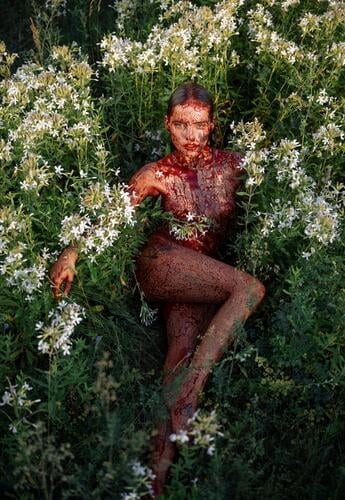 Diese grünen Felder mit weißen Blumen werden von einem nackten Mädchen besetzt, das mit Kunstblut bedeckt ist. Wie eine echte Satansanbeterin fühlt sie sich in ihrer nackten Haut pudelwohl. Eine hübsche Frau sieht aus wie ein Teufel.