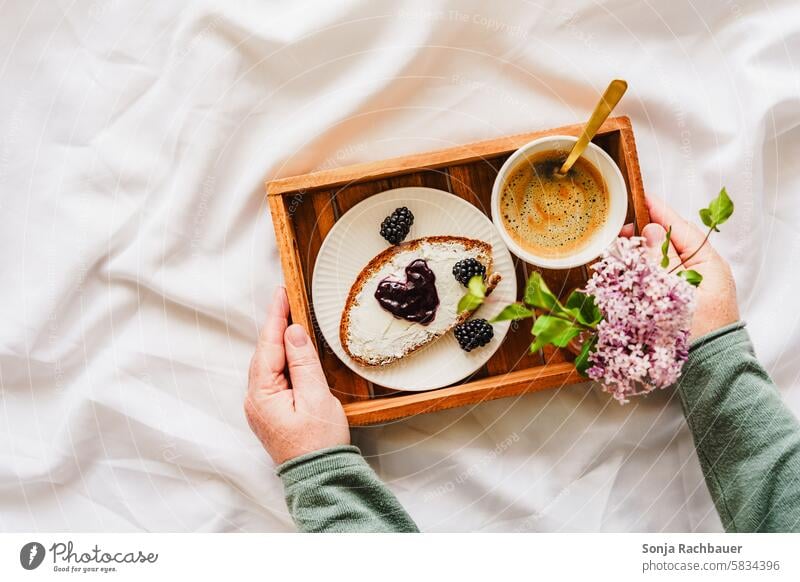 Frühstück im Bett Kaffee Blume Tasse Marmelade Brotscheibe Serviertablett Frau halten Morgen Heißgetränk lecker süß herzförmig Bettdecke weiß Draufsicht