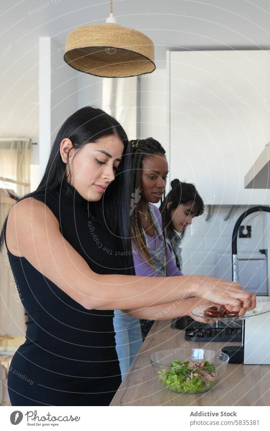 Drei Frauen kochen gemeinsam in einer modernen Küche Essen zubereiten Salatbeilage Teamwork Bestandteil Gesundheit Mahlzeit Vorbereitung Zeitgenosse vielfältig