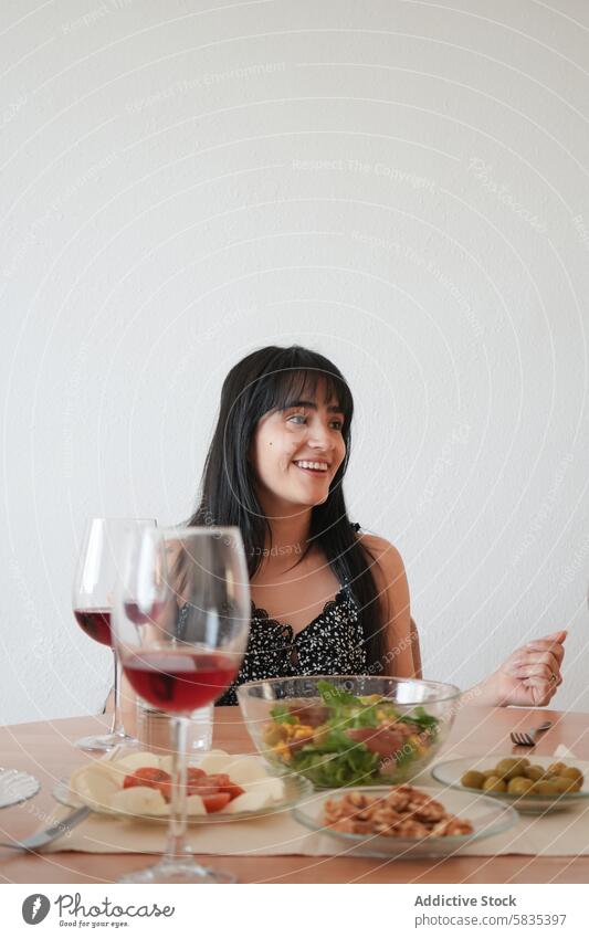 Junge Frau, die eine Mahlzeit mit einem Glas Wein genießt Abendessen Tisch Gesundheit Lebensmittel Salatbeilage oliv heiter Lächeln genießen sitzen jung