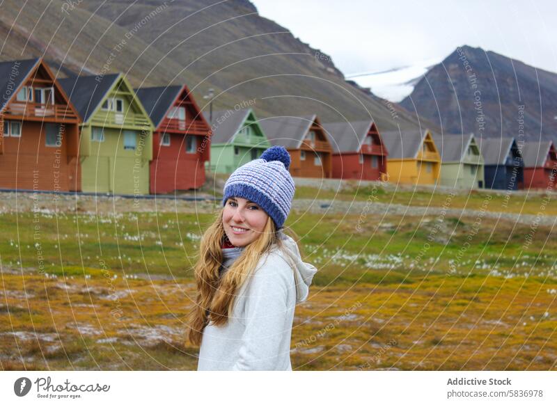 Junge Touristin in Longyearbyen, Svalbard. Sommerliche Abenteuerreise in der norwegischen Arktis. Frau Norwegen farbenfrohe Häuser Beanie Lächeln