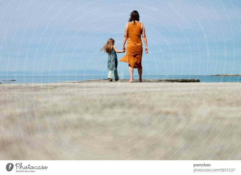 Mutter und Kind gehen Hand in Hand einen Steg  am Meer entlang. mutter liebe händchen halten Glück Zusammensein Familie & Verwandtschaft