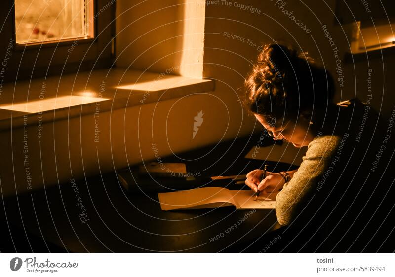 Eine Frau zeichnet am Schreibtisch bei Straßenlampenlicht durch das Fenster Licht zeichnen Künstler Abend Papier Kreativität Kunst Freizeit & Hobby