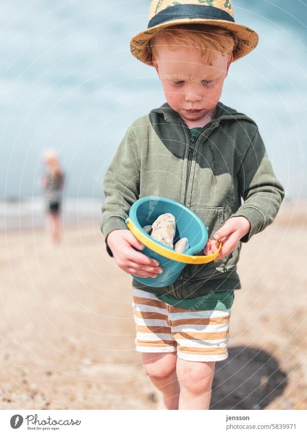 Kleiner Junge spielt am Strand mit einem Eimer voll Steine Urlaub Urlaubsstimmung Ferien & Urlaub & Reisen Sommer Sommerurlaub Strandleben Kind unbeschwert