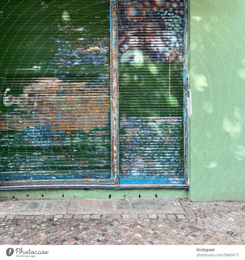 farbige Rolläden vor Ladenfenster bunt grün abgeblättert Rolladen herunterlassen grschlossen Ladengeschäft Farbe Grafitti Hauswand Bürgersteig Sonnenreflexe
