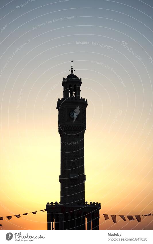 Der Uhrturm von Izmir mit Fahnen und Wimpeln im Licht der untergehenden Sonne am Konak Platz im alten Smyrna am Ägäischen Meer in der Türkei Kleinasien