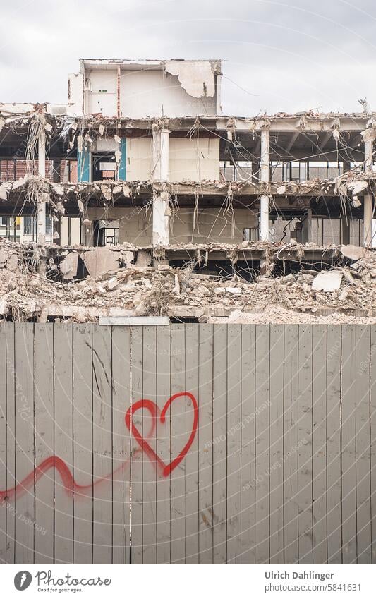 gesrühtes rotes Herz an einem grauen Bauzaun mit Abrissgebäude im Hintergrund Baustelle Sehnsucht Grafitti Melancholie Demontage Hoffnung Vergänglichkeit Liebe