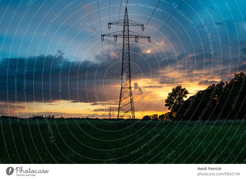 Weit führen Strommast und die Leitungen den Blick ins Bild. Der Abendliche Himmel läst es schon dunkel werden Stromleitung Stromtransport Abendlicht