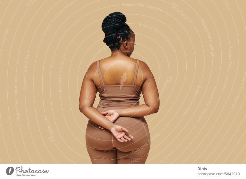 Studio portrait of curvy Black woman in sportswear, view from the back dysmorphia disorder self-acceptance appearance African American female butt figure