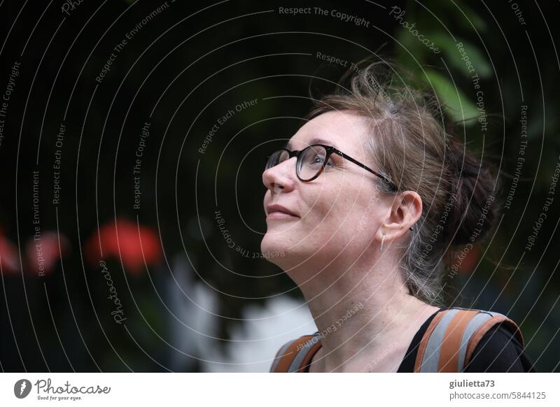 UT Leipzig - heiter bis wolkig | Porträt einer glücklichen, lächelnden Frau mit braunen Haaren und Brille, die interessiert nach oben schaut unterwegs