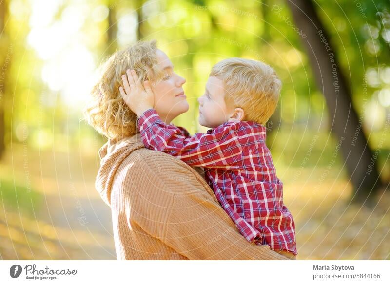Nahaufnahme von Mutter und Sohn bei einem Spaziergang im Herbstpark. Frau hält ihren kleinen Sohn in den Armen und umarmt ihn zärtlich. Junge Mama Komfort