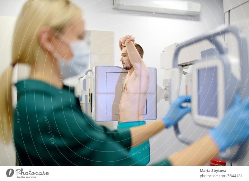 Eine Radiologin macht eine Röntgenaufnahme der Lunge eines Patienten im Röntgenraum einer modernen Klinik. Der Arzt führt eine Fluorographie durch. Die medizinische Untersuchung der Menschen dient der Vorbeugung der Tuberkuloseverbreitung