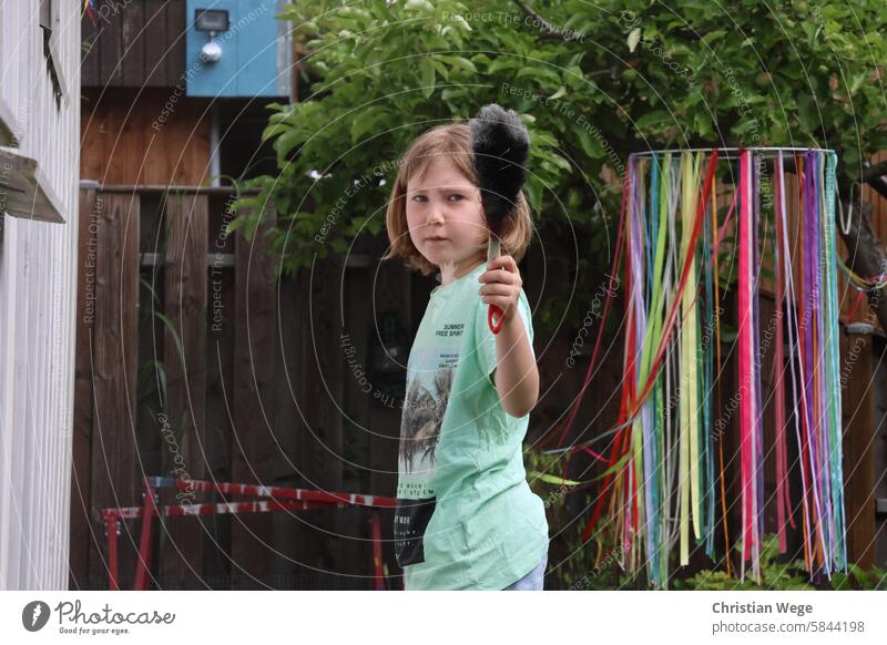 Mädchen schaut grimmig in die Kamera mit einem handbesen Handfeger handfegen feminin böse Blick Mensch bedrohlich Grimasse Blick in die Kamera draußen Garten