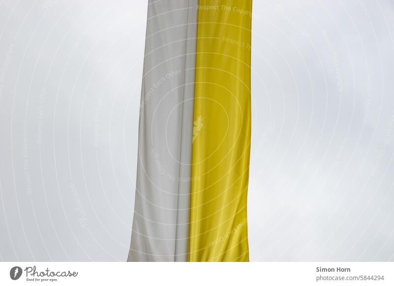 katholische Bannerfahne in gelb-weißer Teilung vor grauem Himmel Fahne Flagge Kirche Symbole & Metaphern grauer Himmel Religion Draperie Christentum