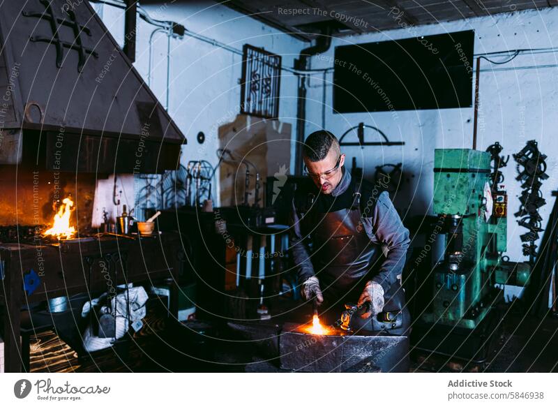 Schmied bei der Arbeit mit heißem Metall in einer Schmiede Hufschmied schmieden Amboss männlich traditionell Werkzeuge Basteln Schmiedekunst Werkstatt Industrie