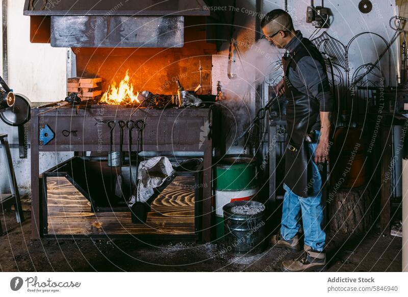 Männlicher Schmied bei der Arbeit in einer traditionellen Schmiede Hufschmied männlich schmieden Flamme Feuer Handwerk Gerät Schutzausrüstung Amboss Hammer