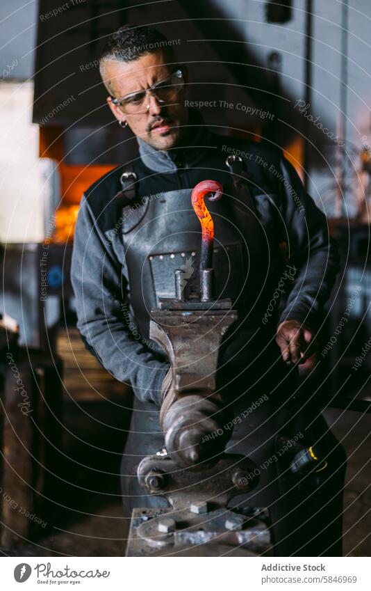 Geschickter Schmied schmiedet ein rotglühendes Eisenstück Hufschmied männlich Schmieden bügeln heiß Amboss Werkstatt Metallbearbeitung Handwerkskunst kompetent