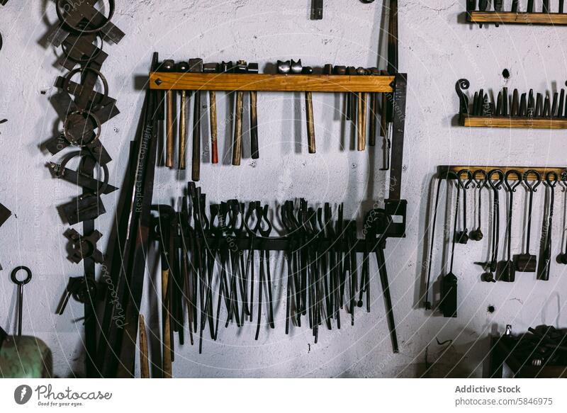 Alte Schmiedewerkzeuge an der Wand in der Werkstatt Hufschmied Werkzeuge altehrwürdig organisiert weiße Wand Kunsthandwerker Hammer Zange Amboss schmieden