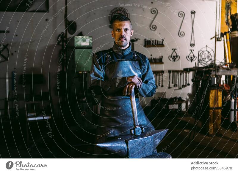 Selbstbewusster Schmied in seiner Werkstatt stehend Hufschmied männlich Schmiede Amboss Hammer industriell Handwerk Kunsthandwerk Metallbearbeitung Fertigung