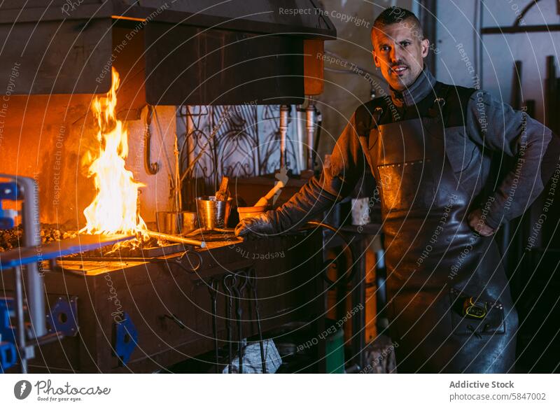 Schmied bei der Arbeit an der Schmiede mit feurigem Hintergrund Hufschmied schmieden Werkstatt Handwerkskunst Fähigkeit männlich traditionell Beruf Industrie