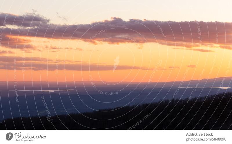 Lebendiger Sonnenuntergang über einer bewaldeten Landschaft mit entferntem See orange rosa Steigung Gelassenheit Wald Hügel Himmel Cloud Abenddämmerung Natur