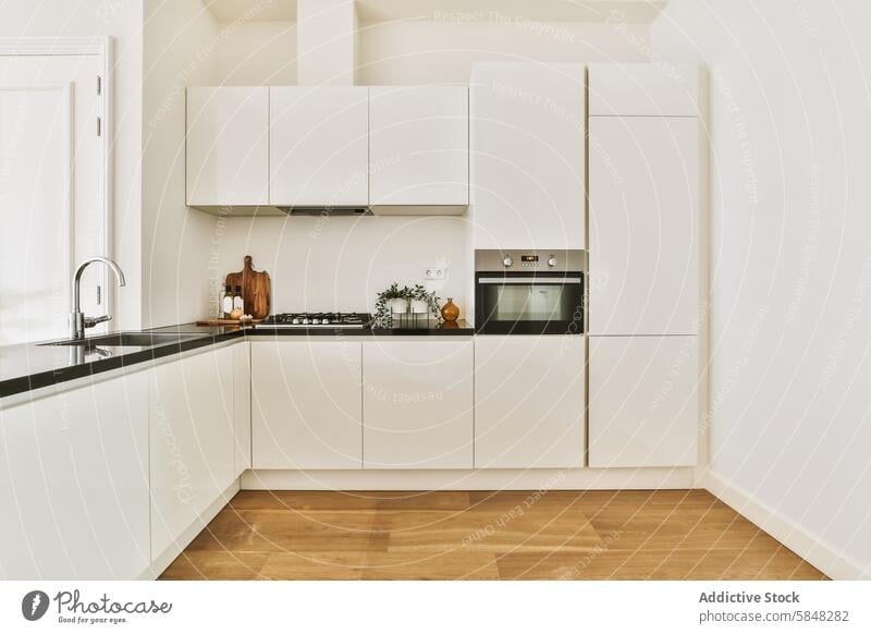 Glatte moderne Küche mit weißen Schränken und Holzfußboden Kabinett hölzern Stock elegant minimalistisch Dekor Arbeitsplatte schwarz eingebaut Ofen Waschbecken