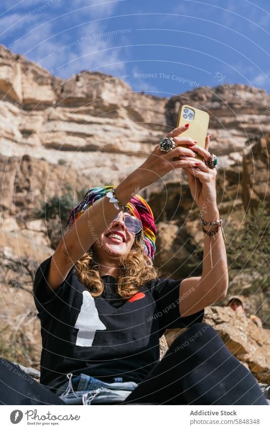 Fröhliche Frau macht Selfie auf einer Bergtour im Oman Smartphone Reisender heiter Abenteuer Berge u. Gebirge robust Hintergrund Fundstück Freude einfangen