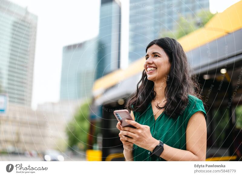 Junge Frau mit Smartphone an der Bushaltestelle in der Stadt Inder echte Menschen Großstadt Spaß Sommer genießend Straße reisen im Freien urban Erwachsener