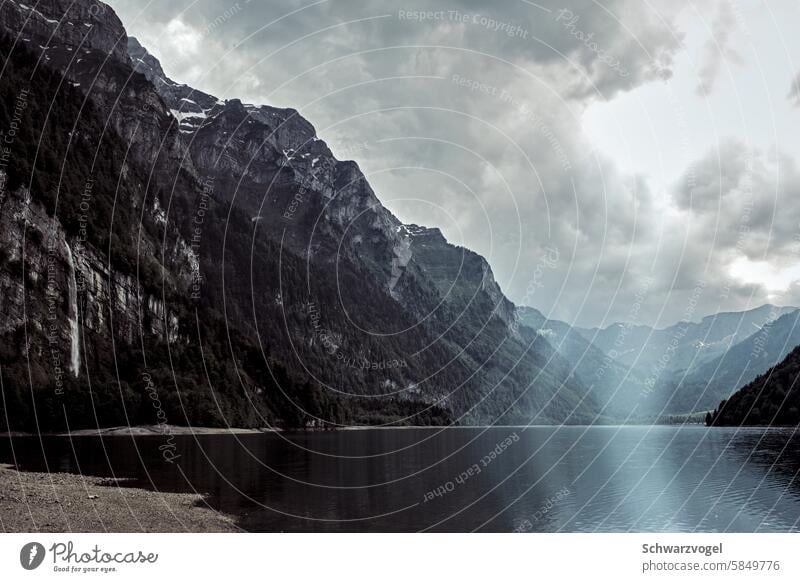 Sonne durchbricht Wolken an einem Bergsee See Schweiz Berge u. Gebirge Alpen Sonnenlicht Lichterscheinung Wasserfall