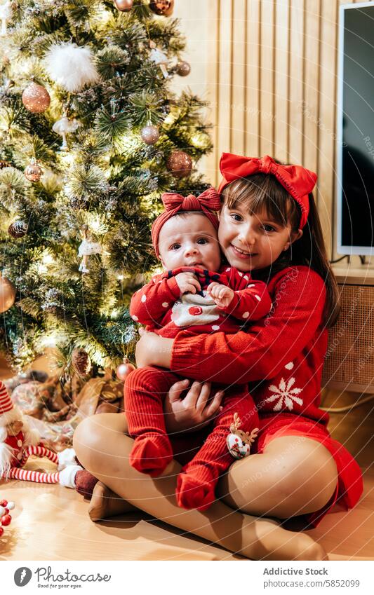 Geschwister feiern Weihnachten gemeinsam zu Hause Familie Feier heimwärts Mädchen Baby festlich rot Outfit dekoriert Weihnachtsbaum Glück Feiertag Saison