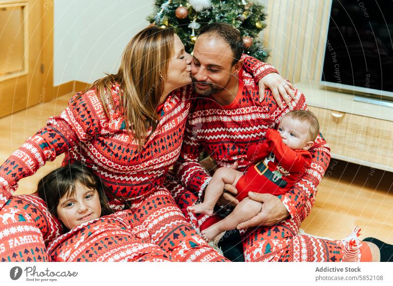 Zärtliche Momente mit der Familie während der Weihnachtsfeier Weihnachten Feier rot Pyjama übereinstimmend liebevoll neugeboren dekoriert Baum festlich Feiertag