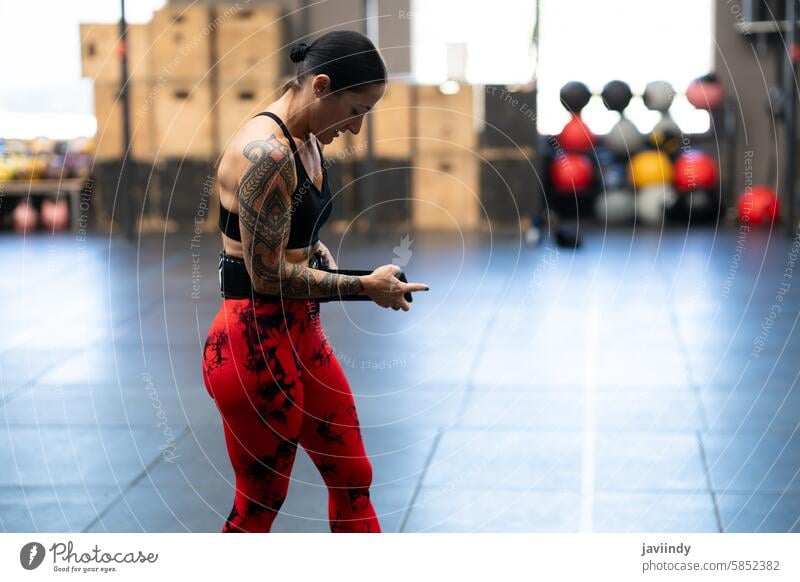 Starke Frau beim Anlegen eines Gürtels beim Gewichtheben stark anfügen Gurt verhindern Verletzungen Cross-Training Fitnessstudio Stärke Gesundheit Wellness