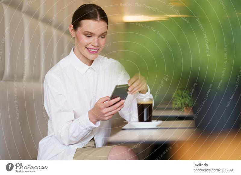 Schöne schicke Frau mit Smartphone in einer Cafeteria sitzend Schönheit Erwachsener Kaukasier Lächeln modern Kantine stylisch entspannt Funktelefon App Mobile